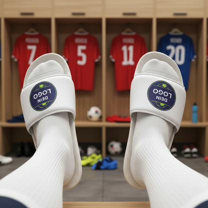 Adiletten in der Kabine getragen, weißer Riemen mit „DEIN LOGO“ vor Spinden im Hintergrund, Adiletten personalisieren