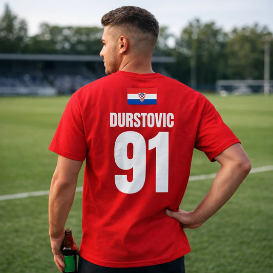 Rotes Kroatien Sauf T-Shirt, Rückseite DURSTOVIC 91, getragen von Mann auf Sportplatz, Kroatien-Flagge am Nacken.